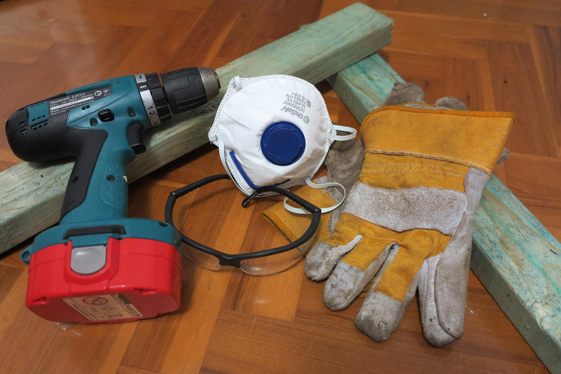 A drill, gloves, disposable face mask scattered on the floor