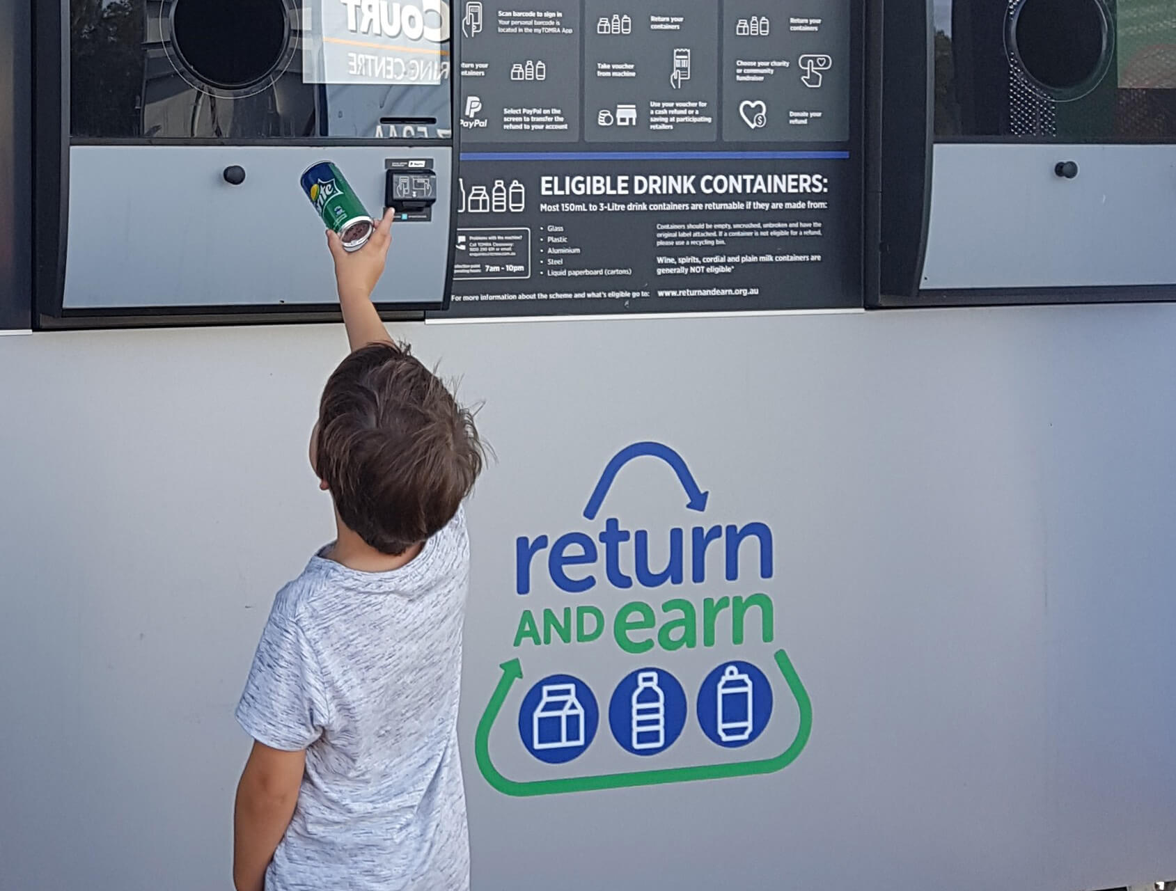 Child inserting  can into a Return and Earn reverse vending machine