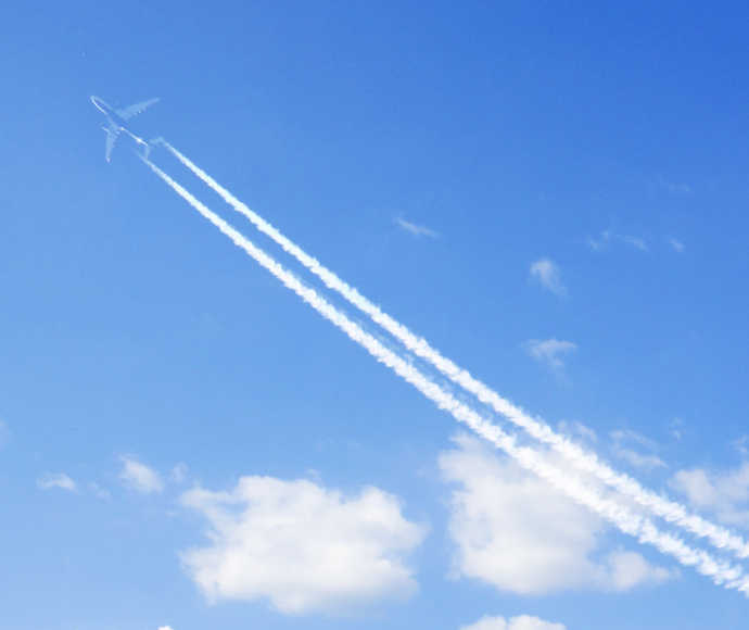 Condensation Trails of a plane in the sky, surrounded by clouds