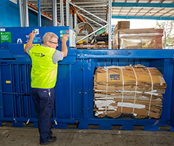 man in h-vis vest operating a cardboard baler