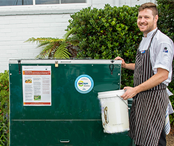 Staffer adding organic material to a large worm farm